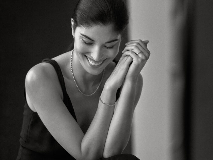 Lifestyle portrait of smiling woman resting her chin on her hands.