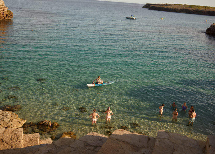 Aerial travel photograph of people swimming and paddleboarding in a cove.