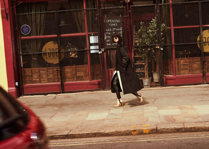 Fashion photography of a person walking past a shopfront.