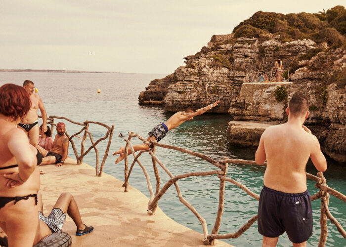 Lifestyle photograph of a group by a rocky coastline behind a wooden fence