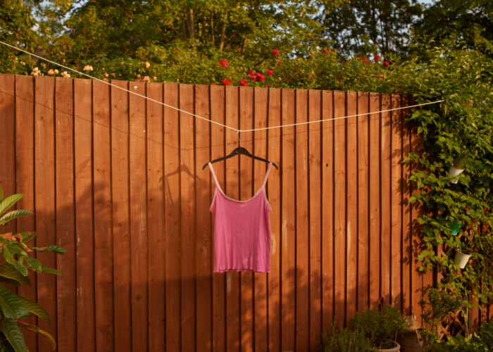 Still life of a pink garment hanging on a wooden fence.