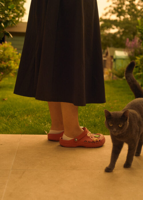 Lifestyle image of a woman's legs and a cat on a garden patio.