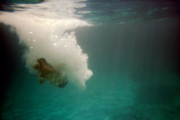 Underwater photograph of a swimmer diving beneath waves.