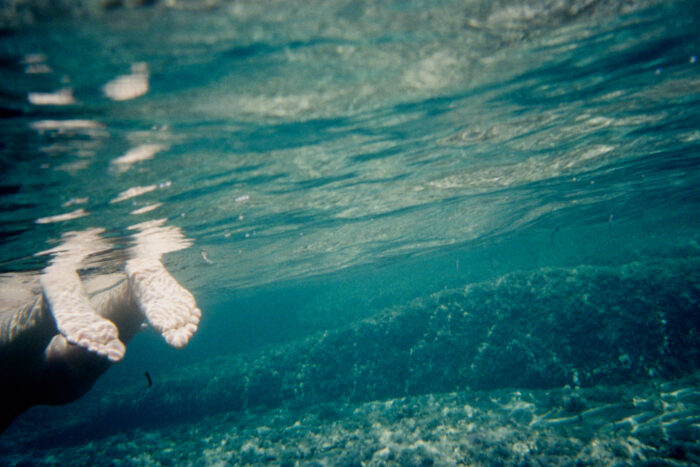Underwater close-up of feet breaking the water's surface.