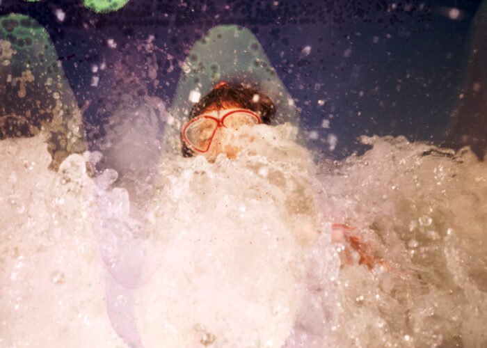 Lifestyle image of a person emerging from a splashing wave.