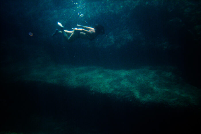 Underwater photograph of a swimmer near a rocky seabed.