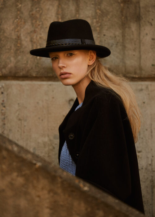 Fashion portrait of woman in wide-brim hat and coat outdoors.