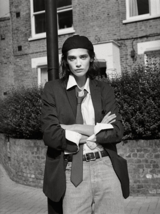Street style portrait of woman in blazer and tie with arms crossed.