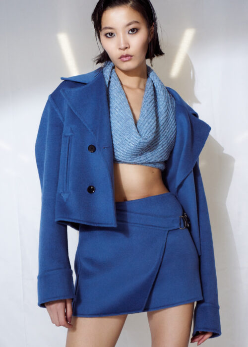 Fashion portrait of woman in blue cropped jacket and matching skirt.