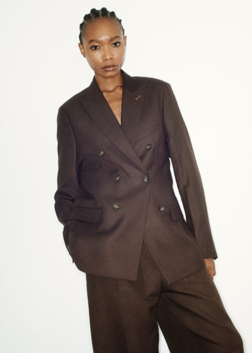 Fashion portrait of woman in brown tailored suit, studio setting.