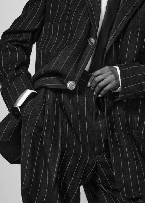 Black-and-white fashion detail of pinstripe suit with hand in pocket.