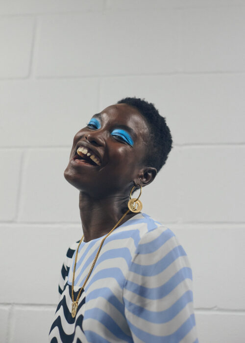 Fashion portrait of laughing woman in striped top with blue eyeshadow.