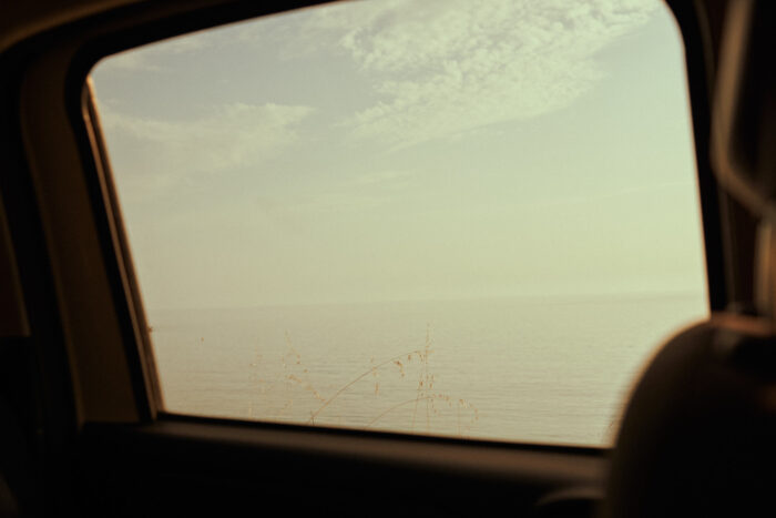 Travel photograph of the sea viewed through a car window.