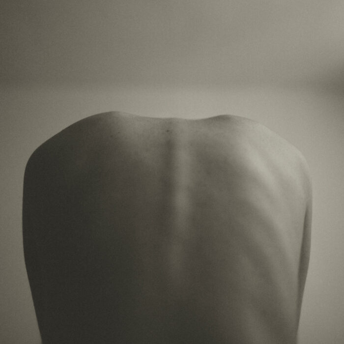 Black-and-white nude study of a woman's back, studio setting.
