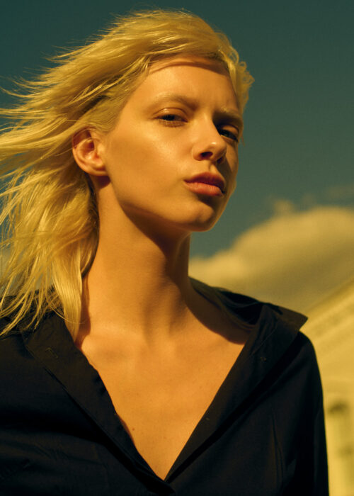 Fashion portrait of woman in dark shirt in outdoor golden light.