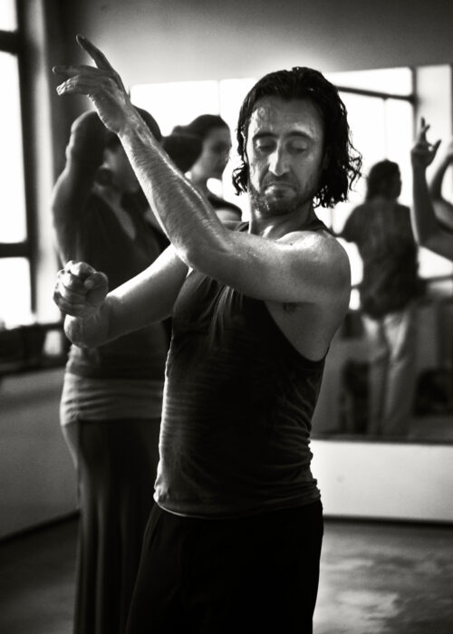 Studio dance photograph of a man and woman performing flamenco in front of a mirror.