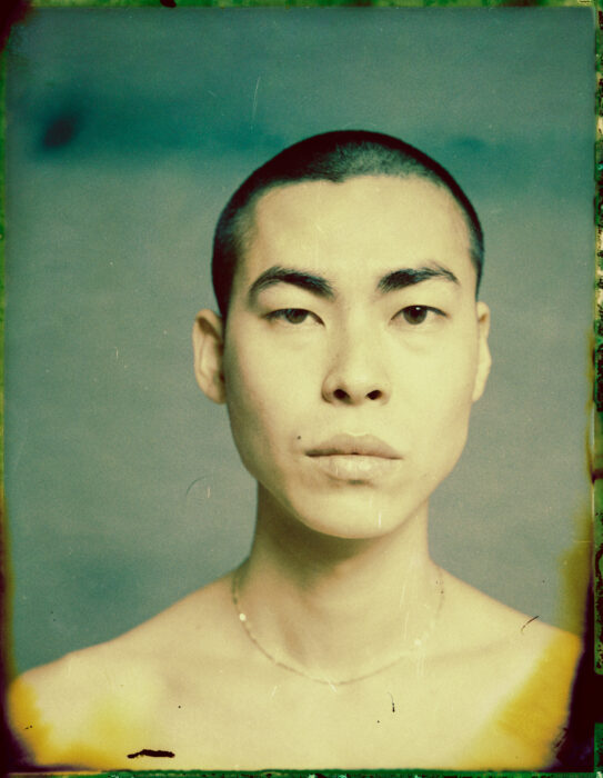 Vintage-toned portrait of man with shaved head, faded colour tones.