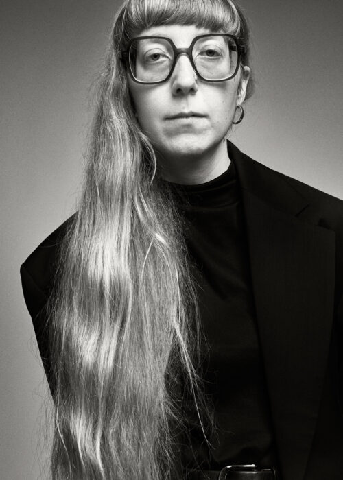 Black-and-white portrait of woman with long hair and glasses dressed in black