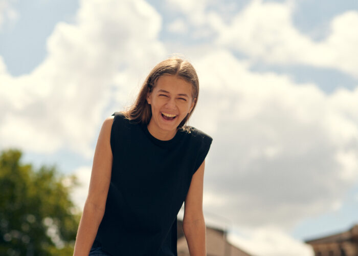 Lifestyle portrait of laughing woman outdoors under a cloudy sky.