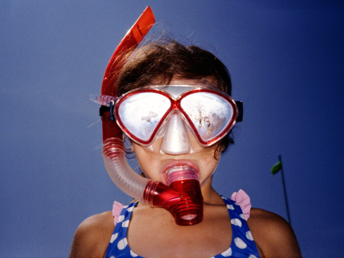 Lifestyle portrait of child wearing a snorkel mask and patterned swimsuit.